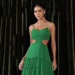 Pessoa em vestido verde elegante com recortes; vestido verde combina com que cor de sapato e bolsa em look sofisticado.
