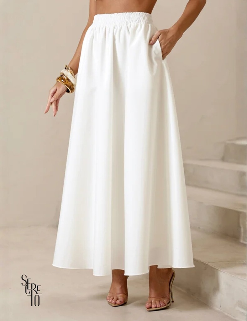 Mulher usando saia longa branca de tecido fluido, com cintura elástica, em produção elegante para o Natal