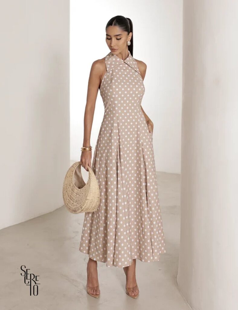 Mulher com vestido midi bege de poá e acessórios dourados, excelente referência de vestidos de convidadas 15 anos para eventos diurnos e modernos.