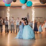 Duas jovens celebram em pista de dança; destaque para vestidos glamourosos, perfeitos como inspiração de vestidos de convidadas 15 anos em festas memoráveis.