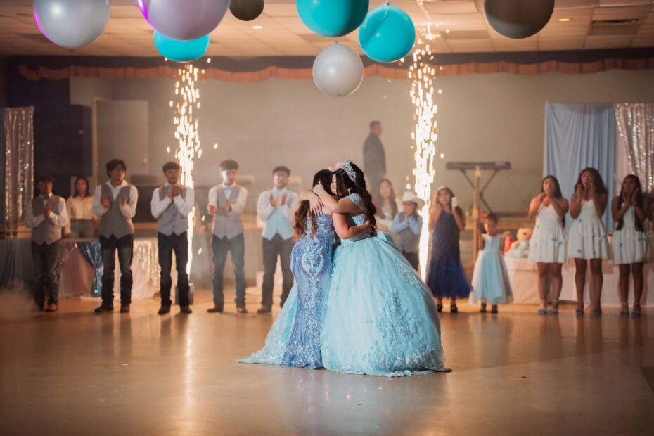 Duas jovens celebram em pista de dança; destaque para vestidos glamourosos, perfeitos como inspiração de vestidos de convidadas 15 anos em festas memoráveis.