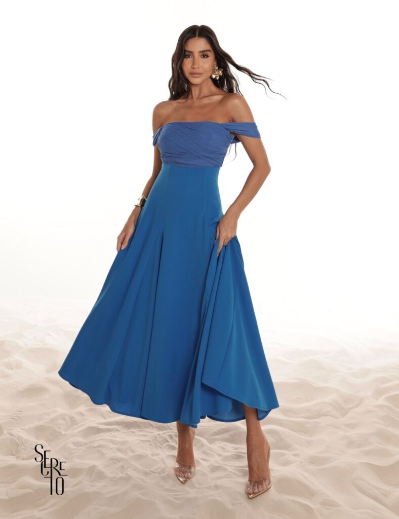 Mulher posa com vestido azul ombro a ombro, ideal como referência de vestidos de convidadas 15 anos em eventos elegantes e ao ar livre.