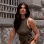 Mulher de cabelo longo usa regata escura, representando um dos tipos de blusas femininas.